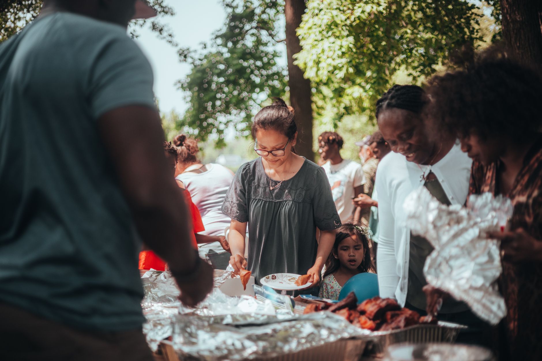 A lively barbecue gathering with diverse group outdoors enjoying food and summer weather.
