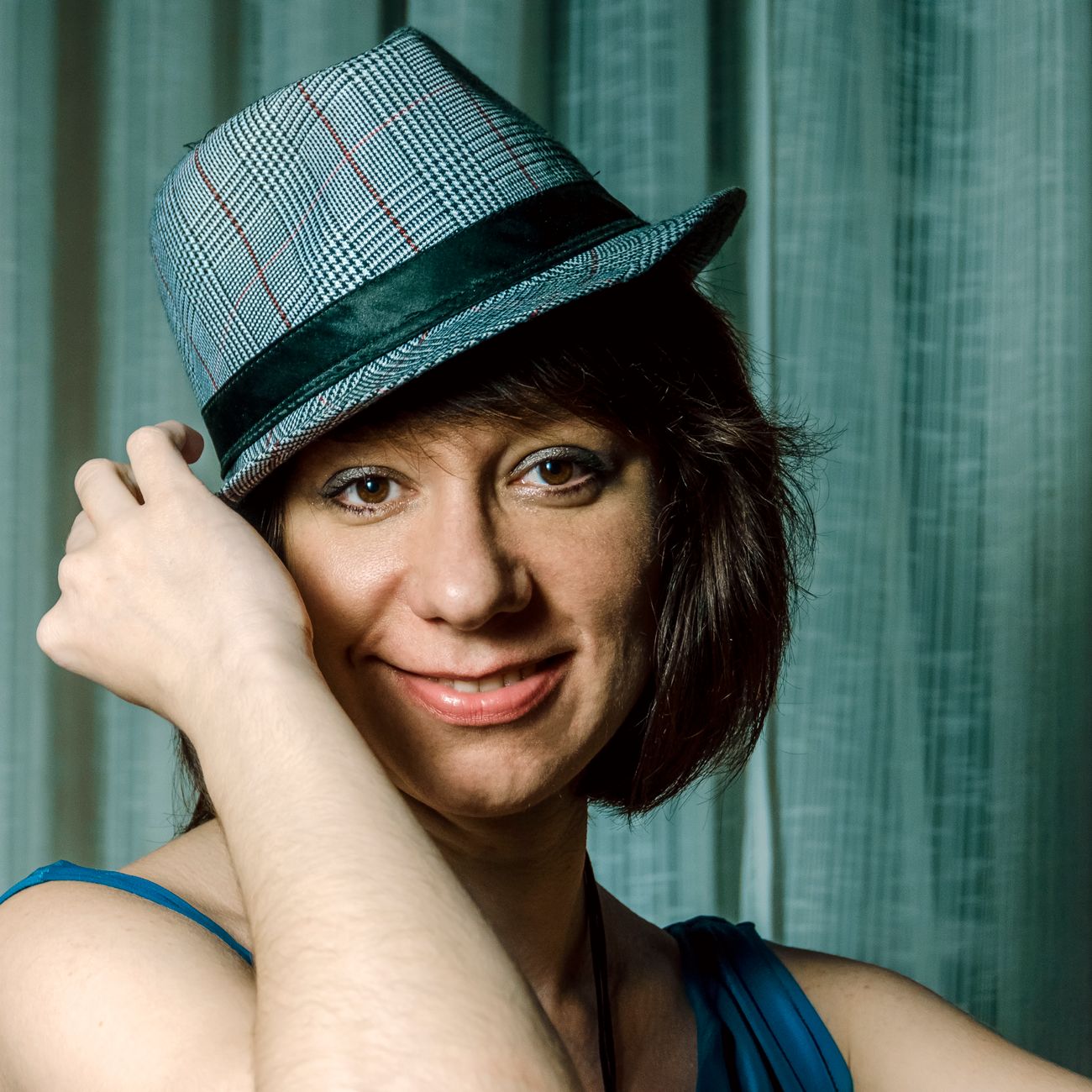 Candid portrait of a woman with a blue fedora, showcasing a friendly smile.