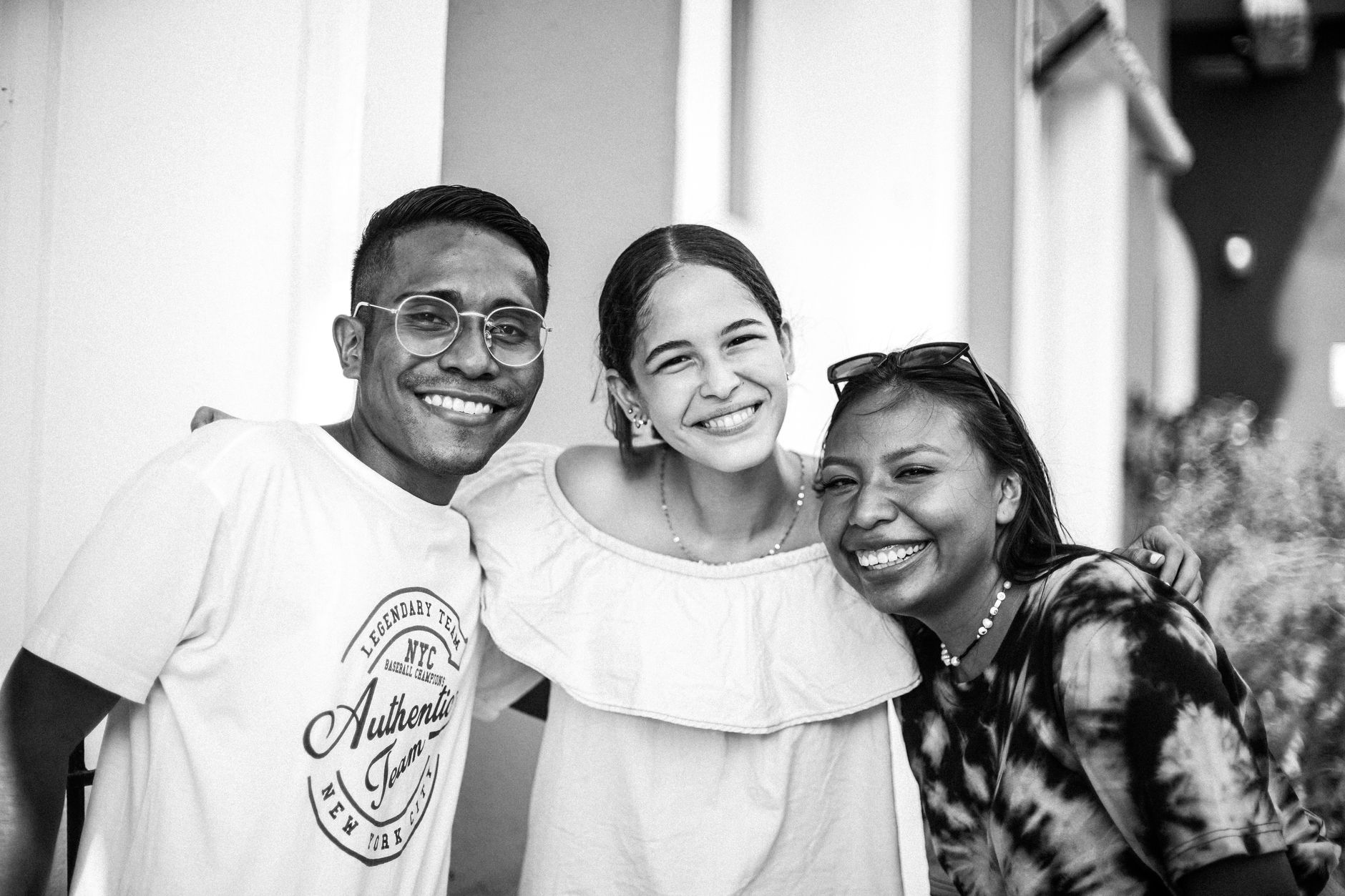 A cheerful group of friends embracing and smiling outdoors, captured in black and white.